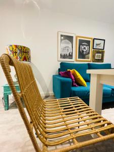 una silla de mimbre en una sala de estar con un sofá azul en Apartamento Puerta Carmona, en Sevilla