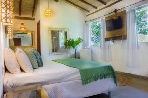 1 dormitorio con 1 cama, TV y ventanas en Pariri Suites, en Trancoso