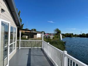 a porch of a house next to a body of water at Chichester Lakeside Holiday Park Lakefront Lodge in Merston