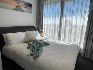 a bed with a blanket on it in front of a window at The Fawkner Apartment Bay-view pool/Gym Free Parking in Melbourne