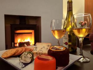 a table with a plate of cheese and a glass of wine at Devana Croft in Tarbert
