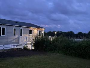 a small house with lights on the side of it at Chichester Lakeside Holiday Park Lakefront Lodge in Merston