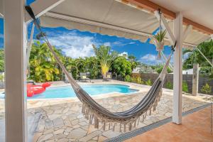 een hangmat op een patio naast een zwembad bij Villa Surelles - 3 chambres - piscine - Le Diamant in Le Diamant