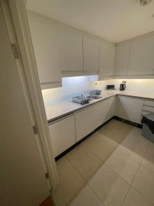a large white kitchen with white cabinets and appliances at Oxford Street Apartment in London