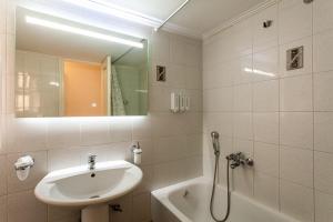 une salle de bains avec lavabo, miroir et baignoire dans l'établissement Kalamata Old City - Minimal Urban Retreat, à Kalamata 16 autres photos