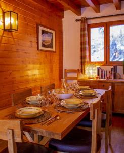 une table en bois avec des assiettes et des verres dans l'établissement Chalet Wallis, Wifi, Garage, Proche des pistes, à Isola