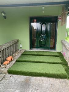 une porte d'entrée d'une maison avec une porte verte dans l'établissement Villa Bimba, alojamiento con piscina y barbacoa, à Caldas de Reis