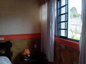a bedroom with a window and a lamp on a table at Pouso do Elefante in Serra do Cipo