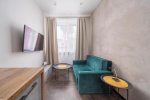 een woonkamer met een groene stoel en een tv bij Lovely 1-bedroom apartment with a free parking in Jūrmala
