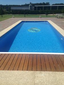 une grande piscine bleue avec une terrasse en bois dans l'établissement Villa Bimba, alojamiento con piscina y barbacoa, à Caldas de Reis