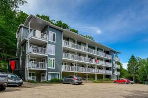 un immeuble d'appartements avec des voitures garées dans un parking dans l'établissement Le Lightroom by Gestion ELITE, à Mont-Tremblant