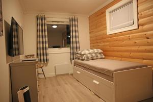 Innsletta holiday home في هارستاد: غرفة نوم بسرير مع جدار خشبي
