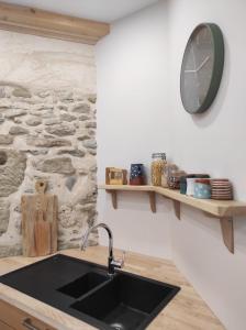 a kitchen with a sink and a clock on the wall at Le Grenier - Chambre d'hôtes 