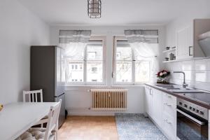 een keuken met witte kasten en een tafel en ramen bij West48 Gemütliches Apartment -Blick auf Blauen See in Duisburg