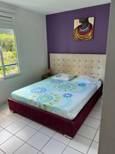 ein Bett in einem Schlafzimmer mit einer lila Wand in der Unterkunft T2 tout confort Vue Panoramique in Sainte-Anne