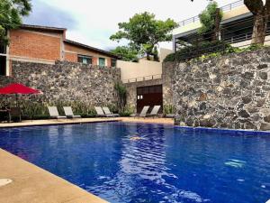 une grande piscine avec des chaises et un mur en pierre dans l'établissement Lujoso departamento Winner, à Cuernavaca