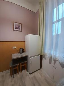 eine Küche mit einem Kühlschrank, einem Tisch und einem Fenster in der Unterkunft Apartment near the train station in Lwiw