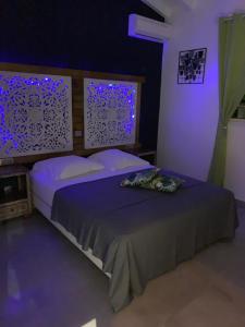 Un dormitorio con una cama con luces moradas. en chez SAM, en Grand-Bourg