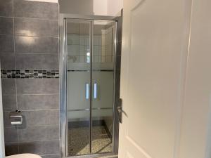 una doccia con porta in vetro in bagno di chez SAM a Grand-Bourg