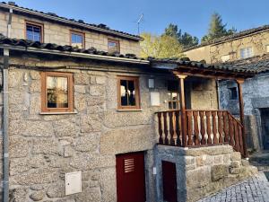 a stone house with a red door and a wooden fence at Casa do Tio Ferreiro in Sabugueiro