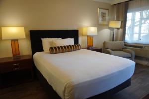 サンタバーバラにあるローズ ガーデン インの大きなベッドと椅子が備わるホテルルームです。