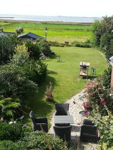 einen Garten mit Stühlen, einem Tisch und einem Feld in der Unterkunft Apartment Seaside in Husum