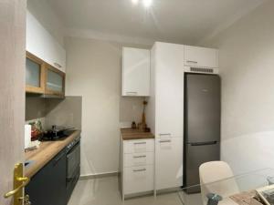 uma cozinha com armários brancos e um frigorífico de aço inoxidável em Crimson Suite: 1-bedroom apartment in Thessaloniki em Tessalônica