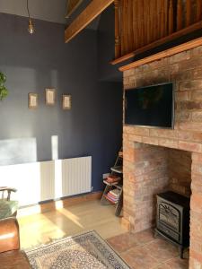 a living room with a brick fireplace with a flat screen tv at The Bolthole barn with wood-fired hot tub in Glentworth