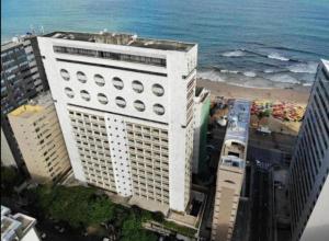 a tall white building next to the ocean at HOTEL NAVEGANTES VISTA PARA MAR Boa Viagem in Recife