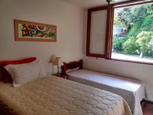 1 dormitorio con cama y ventana en Casa de Campo com Jardim - Albuquerque, en Teresópolis