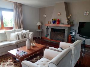 sala de estar con sofás blancos y chimenea en Casa de Campo com Jardim - Albuquerque, en Teresópolis