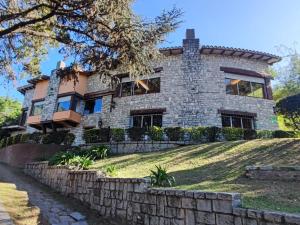 a house on a hill with a stone wall at Las Terrazas Resort & Apart-Cabañas in La Falda