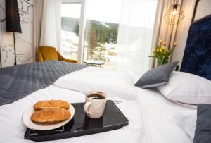 ein Tablett mit zwei Croissants und einem Teller Essen auf dem Bett in der Unterkunft Czarna Góra Biała Perła EnergyApart in Heudorf