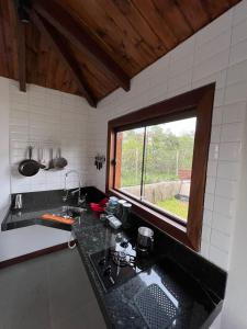 a kitchen with a black counter top and a window at Chalé Lírio do Campo in Ouro Preto