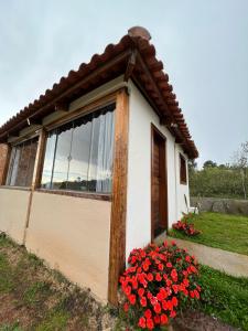 uma pequena casa com flores vermelhas em frente em Chalé Lírio do Campo em Ouro Preto