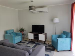 a living room with two blue chairs and a tv at Casa en Sector Oriente de Talca in Talca