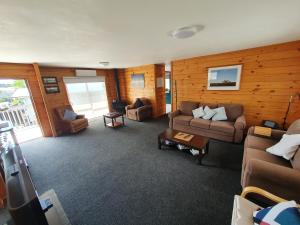 un soggiorno con divani e sedie in una cabina di Pohutukawa Lodge by Orewa Beach a Orewa
