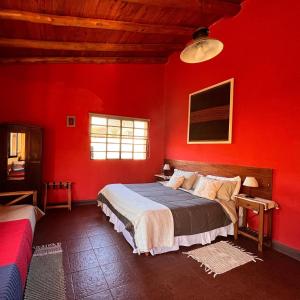 - une chambre avec des murs rouges et un grand lit dans l'établissement Cabañas Taos Pueblo, à Capilla del Monte