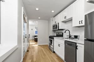 a white kitchen with a sink and a stove at Cozy Ba Townhome Near Little Italy I Fells Point in Baltimore