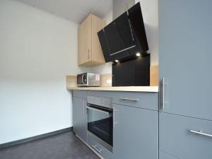 a kitchen with a stove and a microwave at Detached holiday home in Deifeld with balcony, covered terrace and garden in Medebach