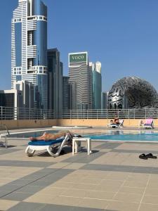 a man laying on a chaise lounge next to a pool at Travelers Backpackers in Dubai