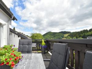 a wooden table and chairs on a balcony with flowers at Detached holiday home in Deifeld with balcony, covered terrace and garden in Medebach