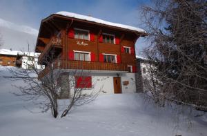 a wooden building with a balcony in the snow at Chalet les Mayens in Saas-Fee