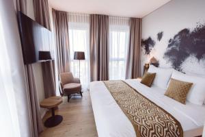 ein Hotelzimmer mit einem großen Bett und einem Stuhl in der Unterkunft Hotel Libertas elements pure in Freiburg im Breisgau
