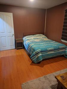 a bedroom with a bed and a wooden floor at atenea in Punta Arenas