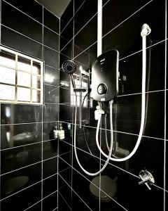 a shower in a black tiled bathroom at Ipoh Deluxe Family Home in Ipoh