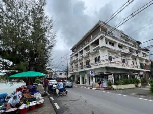 een groep mensen die onder een paraplu voor een gebouw zitten bij Seaside Palace Hotel in Koh Samui 