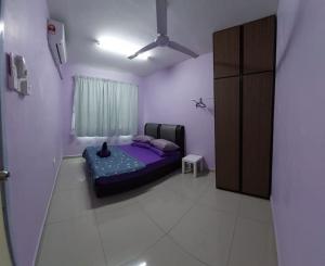 um quarto com uma cama com um gato sentado nela em Homestay Warisan Violet em Malaca