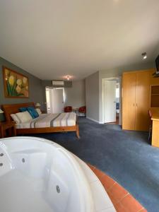 uma casa de banho com uma cama e uma banheira em Waves Luxury Suites em Port Campbell