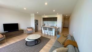 a living room with a couch and a table at Tahuna Beach Apartment in Nelson